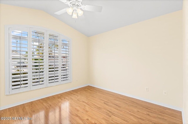 unfurnished room with a ceiling fan, vaulted ceiling, baseboards, and wood finished floors