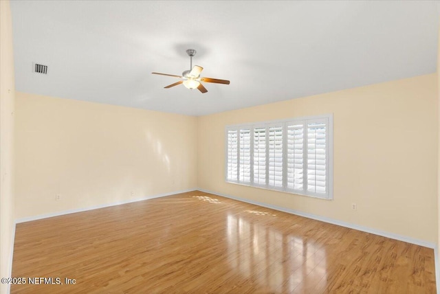 unfurnished room featuring a ceiling fan, visible vents, baseboards, and wood finished floors