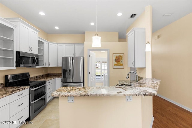 kitchen featuring visible vents, a peninsula, stainless steel appliances, open shelves, and a sink