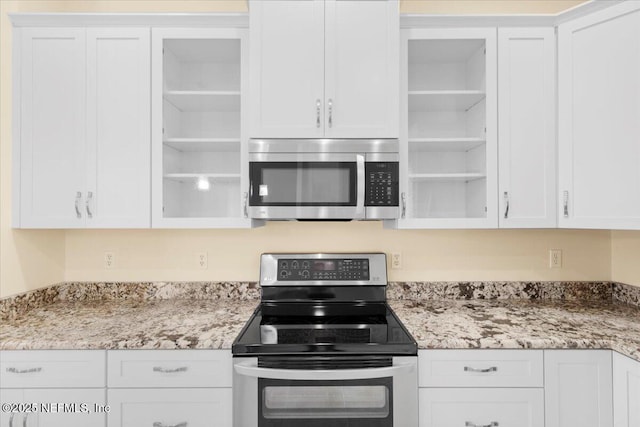 kitchen with white cabinetry, appliances with stainless steel finishes, open shelves, and light stone counters