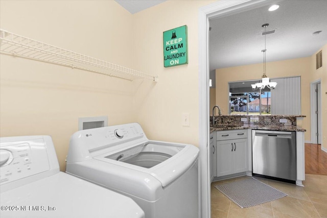 clothes washing area with light tile patterned flooring, a notable chandelier, a sink, visible vents, and washer and dryer