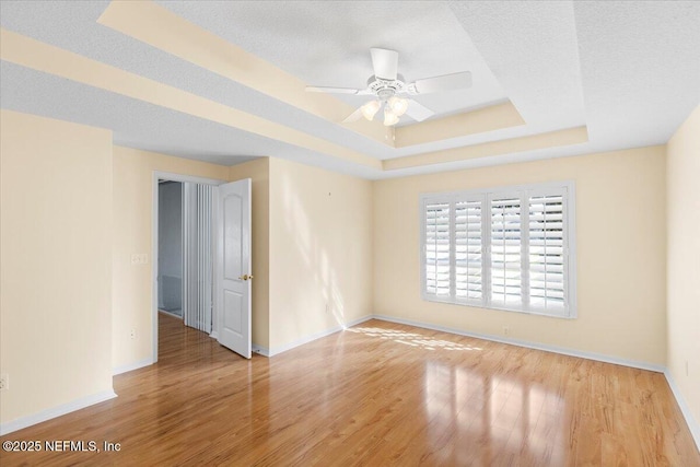 spare room featuring a raised ceiling, a textured ceiling, and wood finished floors