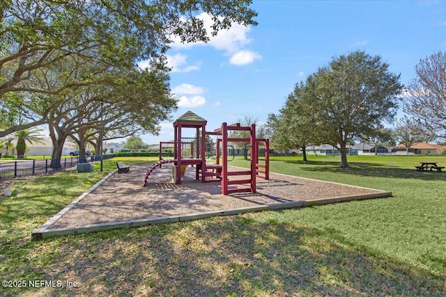 communal playground featuring a yard and fence