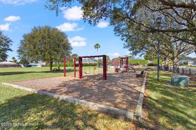 communal playground featuring a lawn and fence