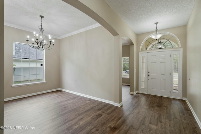 entryway with dark wood-type flooring, arched walkways, a textured ceiling, and baseboards