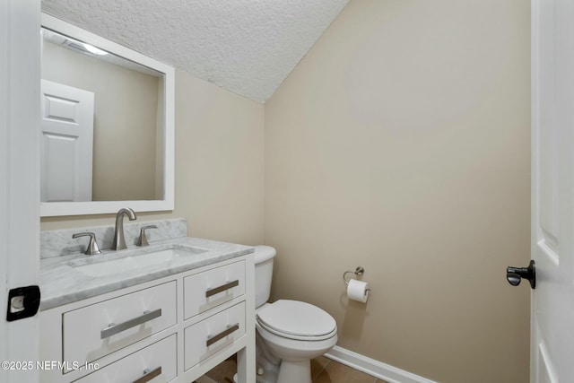 bathroom with toilet, a textured ceiling, vanity, tile patterned flooring, and baseboards