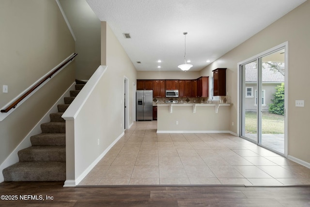 kitchen featuring light tile patterned floors, stainless steel appliances, tasteful backsplash, visible vents, and a peninsula