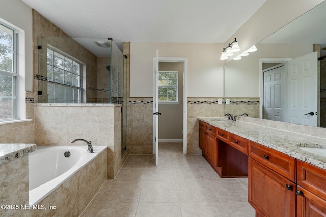 bathroom featuring tile walls, tiled shower, a sink, tile patterned flooring, and a bath