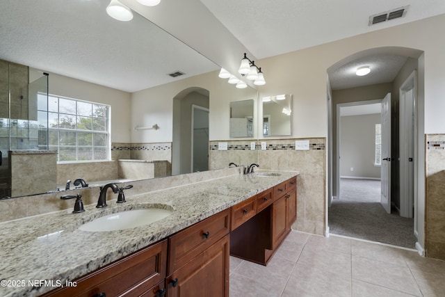 bathroom with visible vents, a sink, tile walls, and a textured ceiling