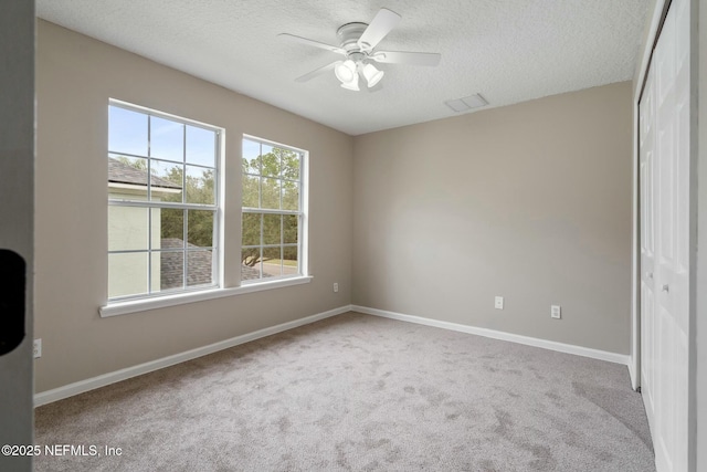 unfurnished bedroom with carpet, a closet, visible vents, a textured ceiling, and baseboards