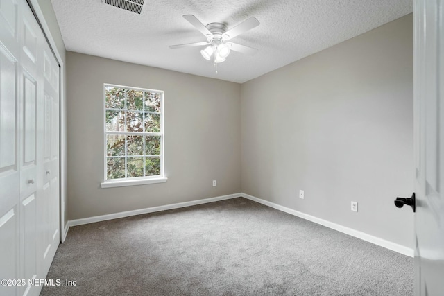 unfurnished bedroom featuring a textured ceiling, visible vents, baseboards, a closet, and carpet