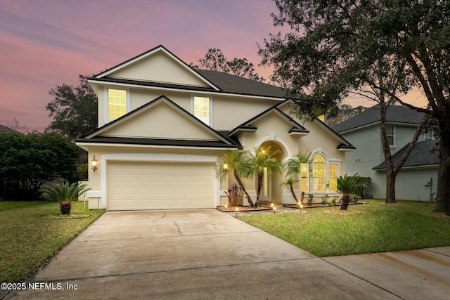 traditional home featuring a garage, driveway, a yard, and stucco siding