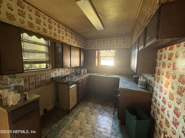 kitchen featuring light countertops, a sink, light floors, and wallpapered walls