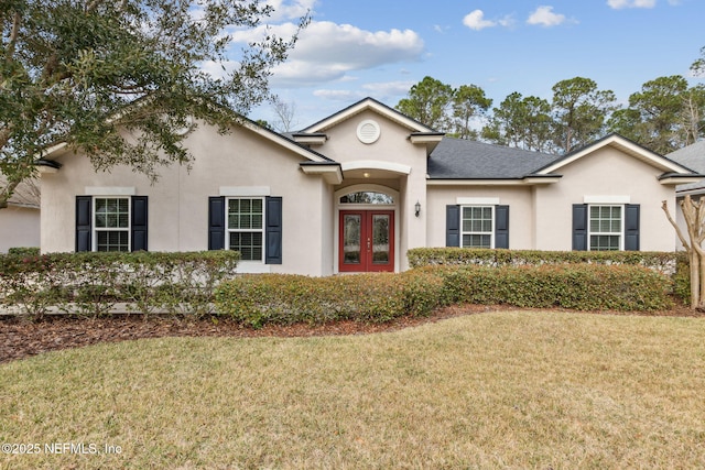 view of front of home featuring a shingled roof, a front lawn, french doors, and stucco siding