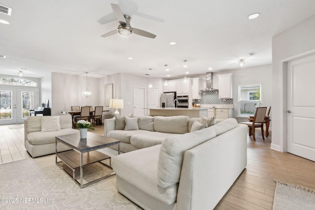 living room with light wood-type flooring, visible vents, recessed lighting, french doors, and ceiling fan