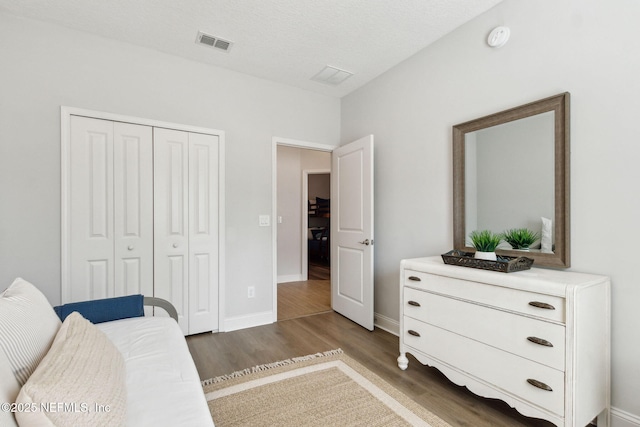 bedroom featuring a closet, visible vents, baseboards, and wood finished floors