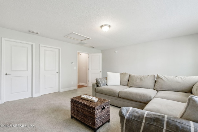 living area featuring visible vents, a textured ceiling, carpet floors, baseboards, and attic access