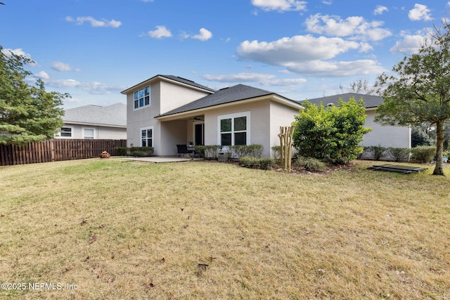 back of house with stucco siding, a patio, a yard, and fence