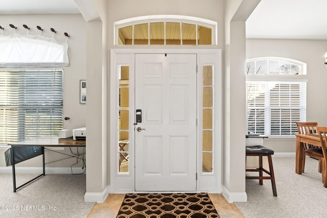 foyer entrance featuring light carpet and baseboards