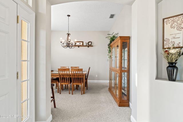 dining space with baseboards, visible vents, an inviting chandelier, a textured ceiling, and carpet flooring