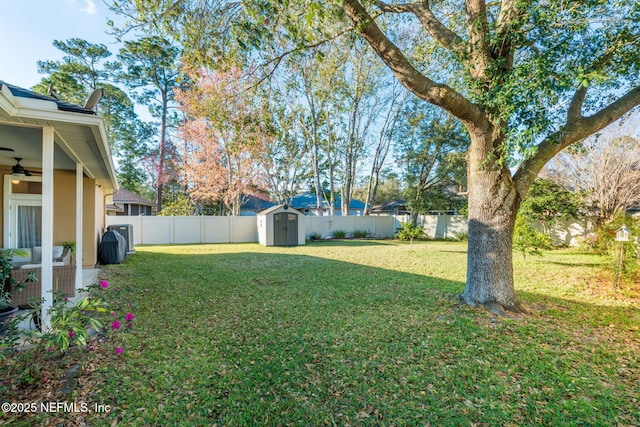 view of yard featuring a storage unit, an outdoor structure, a fenced backyard, and a ceiling fan