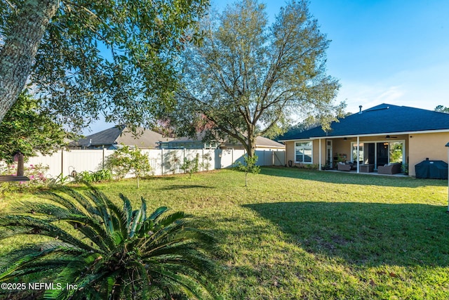 view of yard featuring a fenced backyard, ceiling fan, and a patio