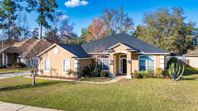 ranch-style house with a shingled roof, a front yard, fence, and stucco siding