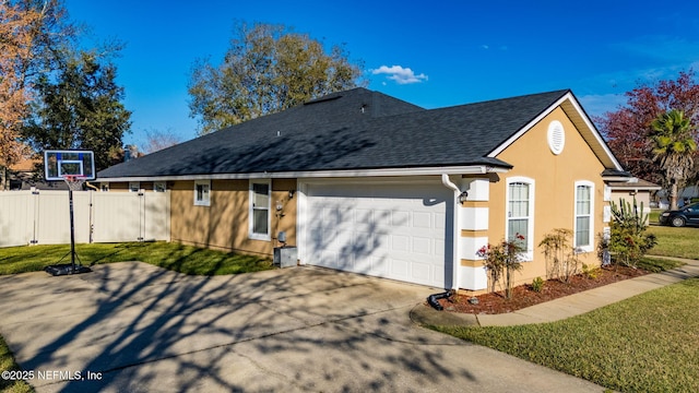 view of side of property with a garage, a yard, roof with shingles, and fence