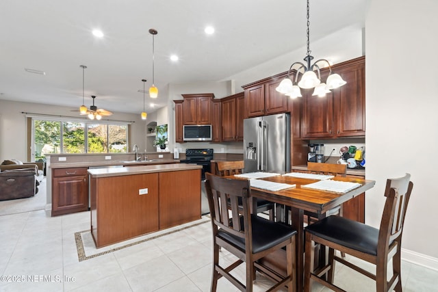 kitchen featuring stainless steel appliances, hanging light fixtures, a peninsula, and ceiling fan with notable chandelier