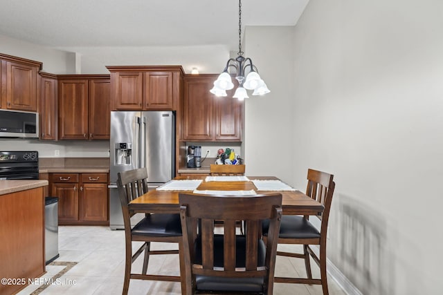 kitchen with light tile patterned floors, stainless steel appliances, light countertops, and an inviting chandelier