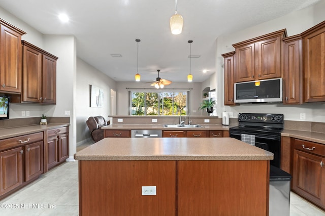 kitchen with decorative light fixtures, light tile patterned floors, stainless steel appliances, a sink, and a kitchen island