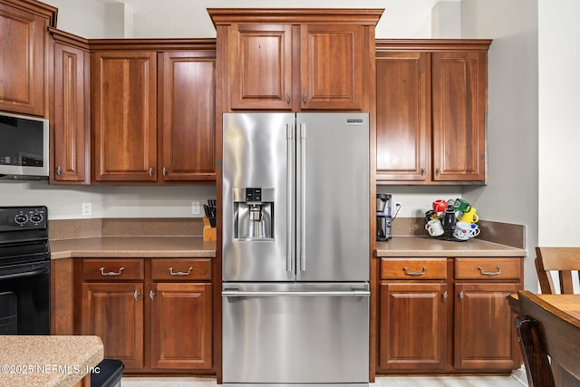 kitchen with brown cabinetry, stainless steel appliances, and light countertops