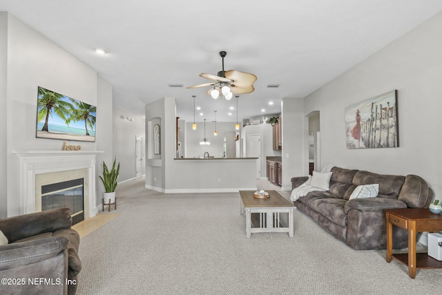 3077 Five Oaks Ln, Green Cove Springs, FL 32043 - living room featuring arched walkways, a ceiling fan, light carpet, a fireplace with flush hearth, and baseboards