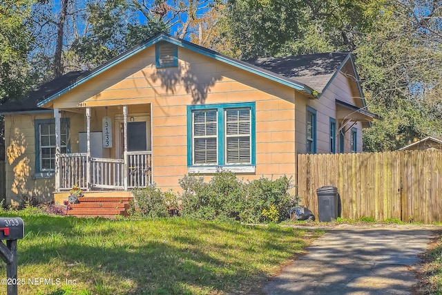 bungalow-style home with a porch, fence, and a front lawn