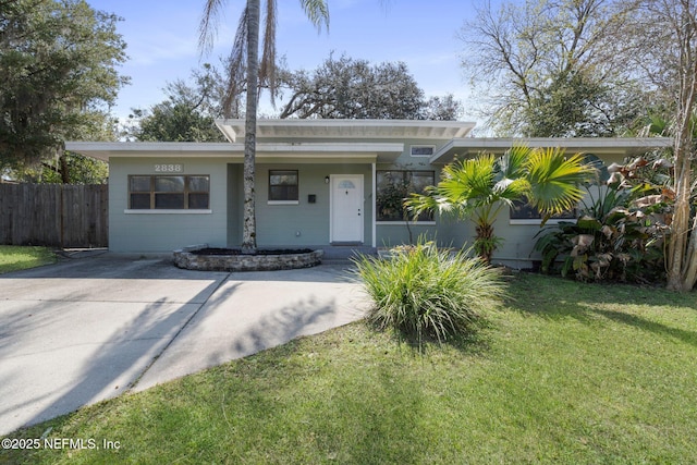 view of front of home with a front yard, concrete block siding, and fence