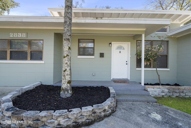 doorway to property featuring a porch and concrete block siding