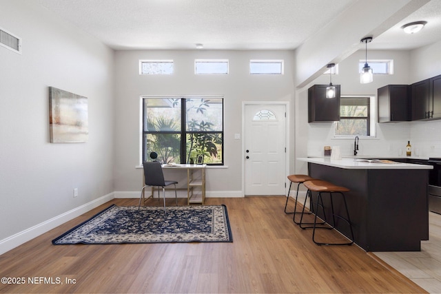 kitchen featuring decorative backsplash, light countertops, light wood-style flooring, and a kitchen bar