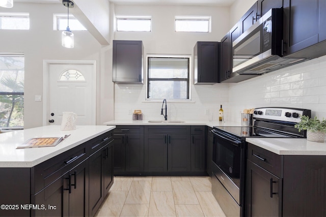 kitchen with stainless steel appliances, a healthy amount of sunlight, light countertops, and a sink