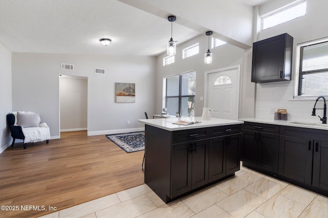 kitchen featuring a wealth of natural light, visible vents, a sink, and dark cabinetry