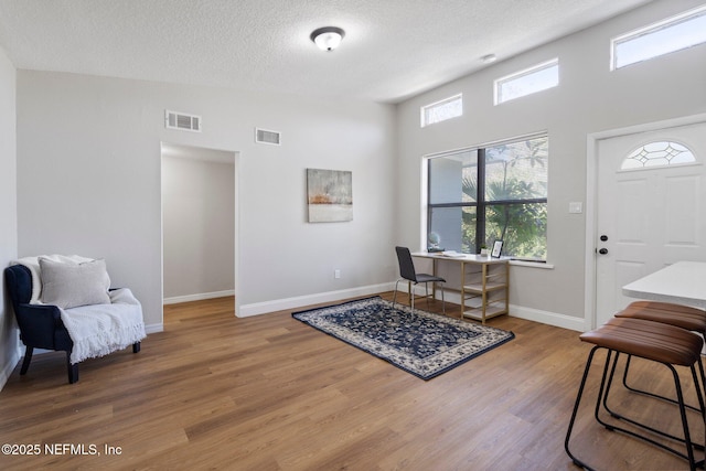 entrance foyer with baseboards, a textured ceiling, visible vents, and wood finished floors