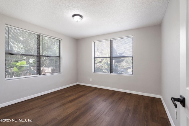 empty room with dark wood-type flooring, a textured ceiling, and baseboards