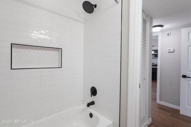 bathroom featuring shower / washtub combination, a textured ceiling, baseboards, and wood finished floors