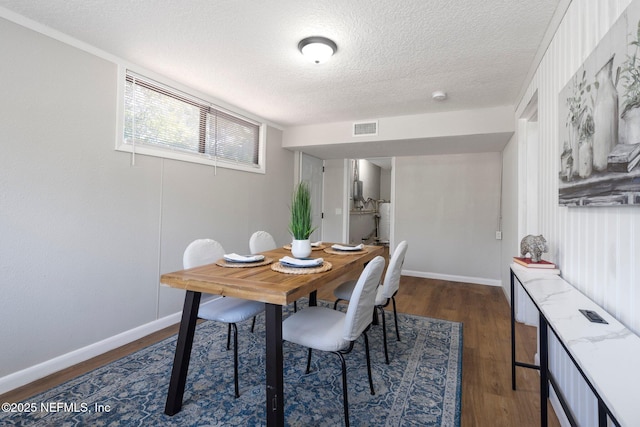 dining space featuring dark wood-type flooring, visible vents, a textured ceiling, and baseboards