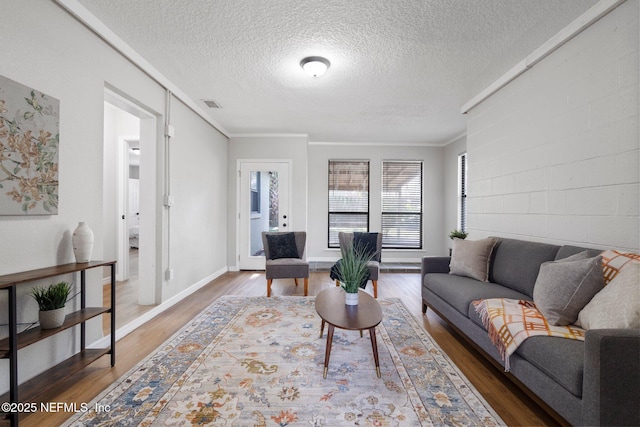 living room featuring concrete block wall, visible vents, and wood finished floors