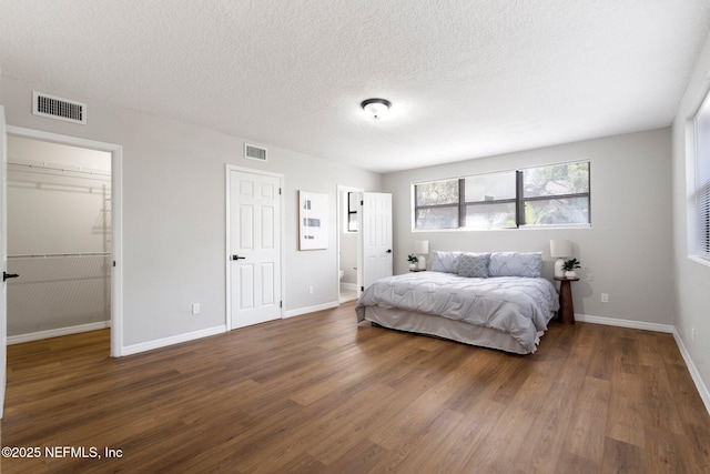 bedroom with baseboards, visible vents, and dark wood-type flooring