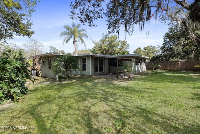 back of property featuring a yard, cooling unit, and fence