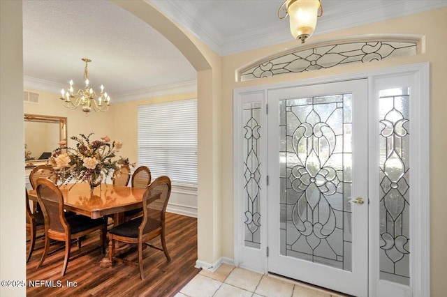 foyer featuring visible vents, arched walkways, a notable chandelier, and ornamental molding