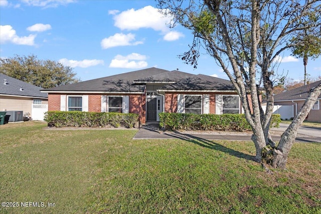 single story home with a front yard, brick siding, fence, and central AC unit