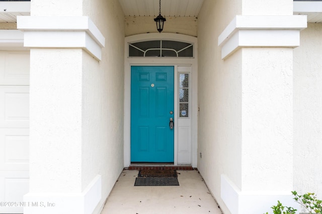 entrance to property featuring an attached garage and stucco siding