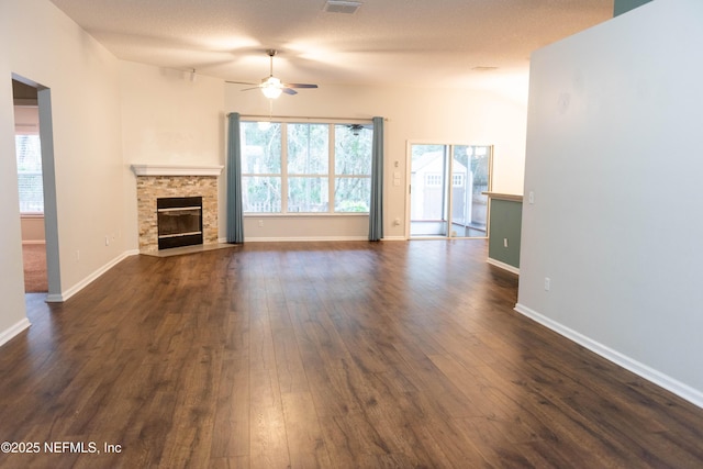 unfurnished living room with dark wood-type flooring, a fireplace, a wealth of natural light, and a ceiling fan